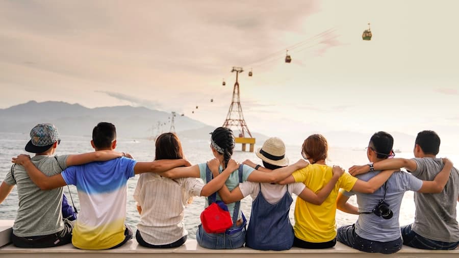 Friends with arms linked, watching a seaside cable car